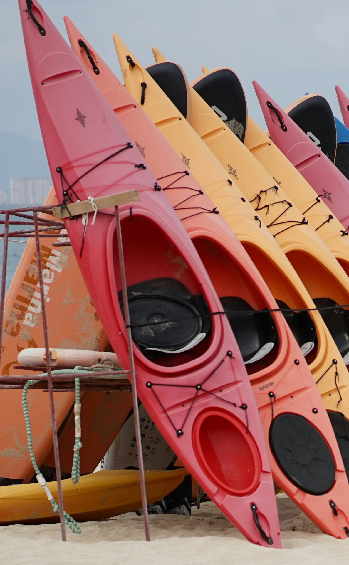 Kayaks de colores apilados en la playa listos para alquilar